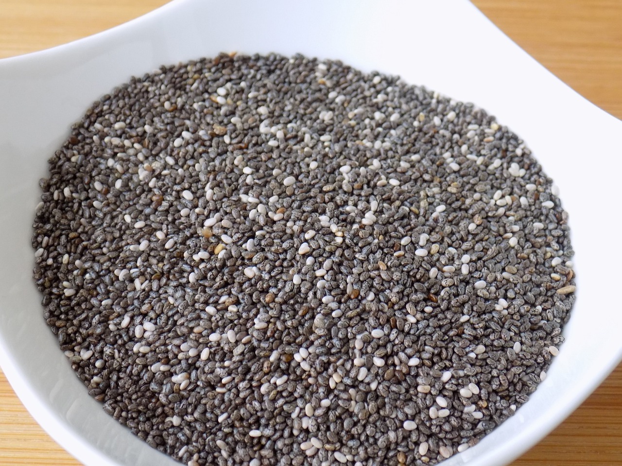 Semi di chia in un cucchiaio, circondati da ingredienti salutari per una dieta equilibrata.