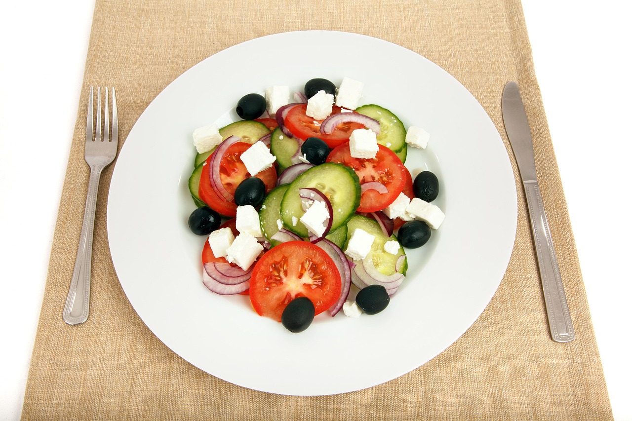 Insalata greca con feta, cetrioli croccanti, pomodori e olive in una ciotola colorata.