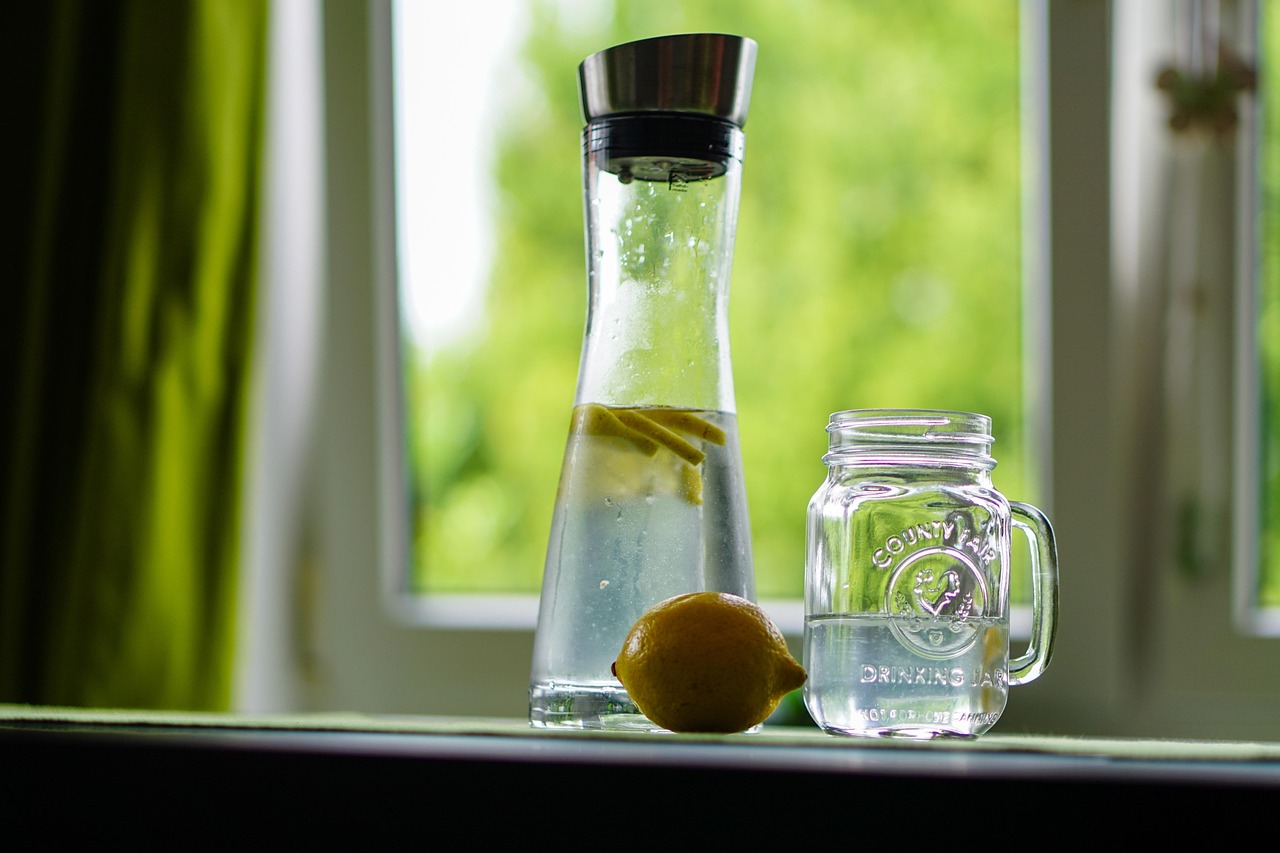 Acqua con limone in un bicchiere, simbolo di salute e benessere per digestione e pelle.