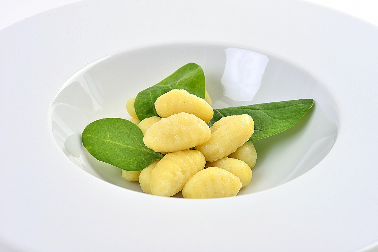 Gnocchi alle zucchine con menta e limone, serviti in un piatto bianco decorato con foglie di menta.
