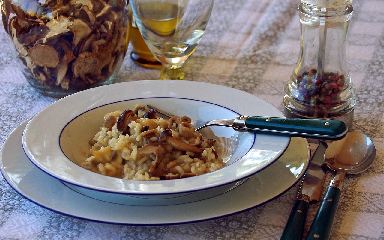 Risotto ai funghi porcini guarnito con crema di parmigiano, servito in un piatto elegante.