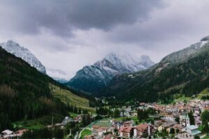 Borgo trentino con paesaggio innevato estivo e montagne sullo sfondo, un microclima affascinante.