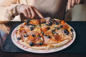 Pizza su un tavolo con un misuratore di glicemia accanto, evidenziando le preoccupazioni per la salute.